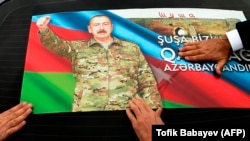 People attach a photo of Azerbaijani President Ilham Aliyev to the rear window of a car as they celebrate the country's declared victory over Armenia in a war over the breakaway Nagorno-Karabakh region.