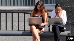 Teenage girls work on laptop computers while wating for a public bus in Moscow. After decades of of foreign travel, imported goods, and access to the Internet, it remains to be seen if ordinary Russians would welcome being cut off from the rest of the world. 