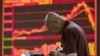 An investor takes notes in front of an electronic board showing stock information at a brokerage office in Beijing on July 7 as China's stock market crashed.