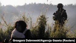 Польскія паліцыянты і памежнікі ахоўваюць групу мігрантаў, якія спрабавалі перасекчы мяжу паміж Беларусьсю і Польшчай каля вёскі Ўснар Горны, Падляскае ваяводзтва. 22 жніўня 2021 году. Ілюстрацыйнае фота