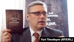 Former Prime Minister Mikhail Kasyanov holds up a copy of the report "Putin. Corruption," at its presentation on March 28.