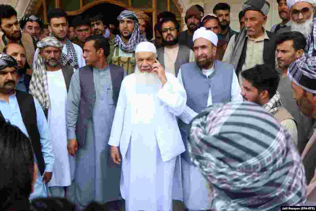 Ismail Khan (on telephone), a veteran of the Soviet-Afghan war of the 1980s, with supporters as he prepares to defend the area against the Taliban advance on July 9. Khan survived an assassination attempt by the Taliban in 2009. 