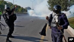 Pakistani police fire tear gas toward protesters marching toward Islamabad on November 26.