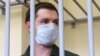 Trevor Reed stands inside a defendants' cage during a court hearing in Moscow in July 2020.