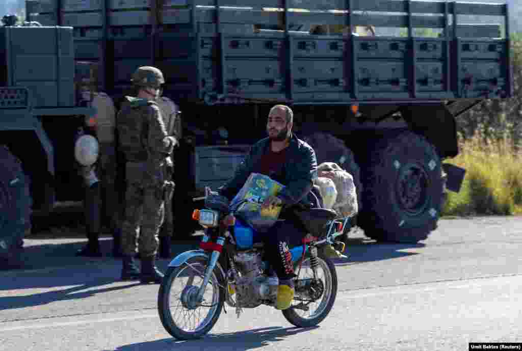 A local man rides past a Russian convoy near the Hmeimim air base. "The locals are just watching," Bektas says of the situation around the base, which is now without external military protection along its perimeter. "There are lots of shops with the Russian alphabet on them in the village close to the air base," Bektas says, but all are now closed. "There aren't any Russian soldiers going out individually or in non-armored cars or anything like that." 
