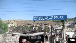 Pakistani gather around the wreckage of a police truck torched by demonstrators in Abbottabad on April 12.