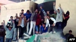 A video grab shows anti-government demonstrators destroying a monument in Tobruk, Libya