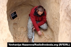 A researcher in the tomb of the Scythian warrior. On right are the bones of a young bull that was sacrificed with the man.