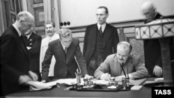 Soviet Foreign Minister Vyacheslav Molotov signs the nonaggression pact between Germany and the Soviet Union in Moscow on August 23, 1939, as Soviet dictator Josef Stalin looks on (left rear).