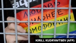 A gay-rights activist holds a poster reading "Love is stronger than homophobia!" while siting inside a police van after his detention during an unauthorized rally in central Moscow in May.