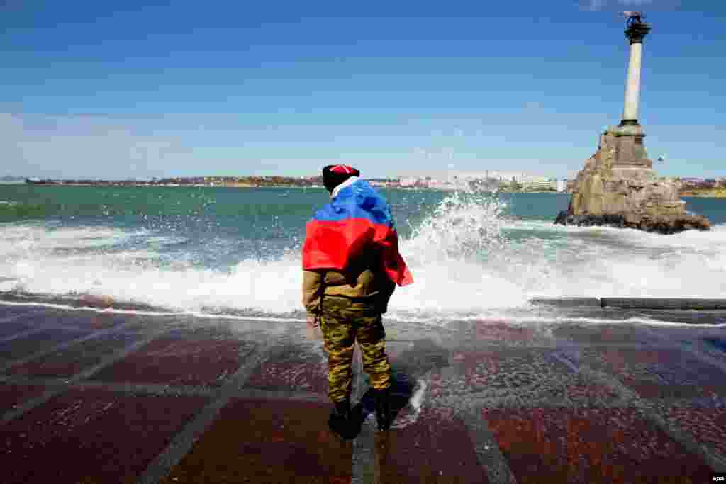 A man draped in the Russian flag stands on the coast of Sevastopol on a stormy day in March. With the Crimean Peninsula firmly under Russian control, on April 7 the stage was set for war when pro-Russian groups in Donetsk and Luhansk burst into government offices and helped themselves to weaponry. Kyiv responded by announcing the start of a "counterterrorism" operation.