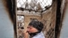 An ethnic Uzbek woman cries as she passes by a burned-out house in the town of Osh on June 24.