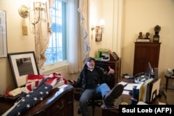 One of the violent pro-Trump supporters who breached the Capitol sits inside the office of the speaker of the U.S. House of Representatives, Nancy Pelosi.