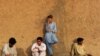 Villagers , their clothes stained with the blood of victims, rest after helping with rescue efforts following a suicide bombing near a mosque in the semi-tribal village of Darra, Pakistan