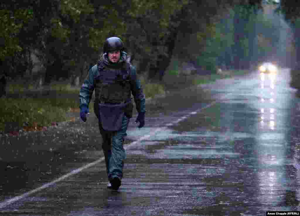As rain and mortar shells fall, van Helten walks to the end of the road to check the painting. 