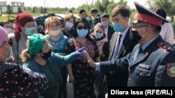 Полиция қызметкері және әкімдік алдына жиналған әйелдер. Шымкент, 30 наурыз 2020 жыл.