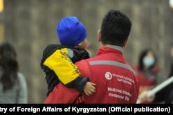 A Red Crescent worker holds a child who has returned from Iraq to Kyrgyzstan. (file photo)