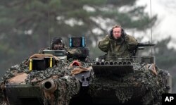 Самый популярный политик Германии, министр обороны Борис Писториус (справа), испытывает танк Leopard 2 на военном полигоне