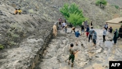 Afghan villagers shovel mud on July 15 following flash floods after heavy rainfall in the Dara district of Panjshir Province.