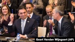 NATO Secretary-General Jens Stoltenberg (right) looks at Macedonian Foreign Minister Nikola Dimitrov as he holds a pen aloft during the signing of an "accession protocol" in a ceremony at NATO headquarters in Brussels on February 6. 