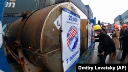 Representatives of participating companies sign containers with uranium to be used as fuel for nuclear reactors, prior to loading them aboard a ship in St. Petersburg.