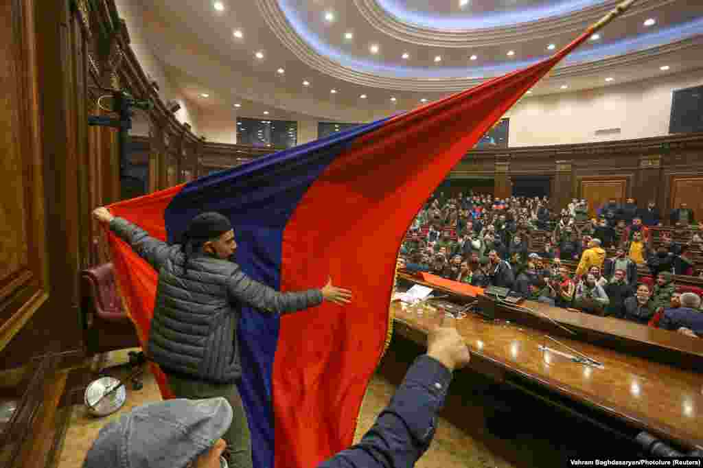 Protesters put up an Armenian flag inside of parliament. Objects were thrown, chairs smashed, and scuffles broke out at the podium. 