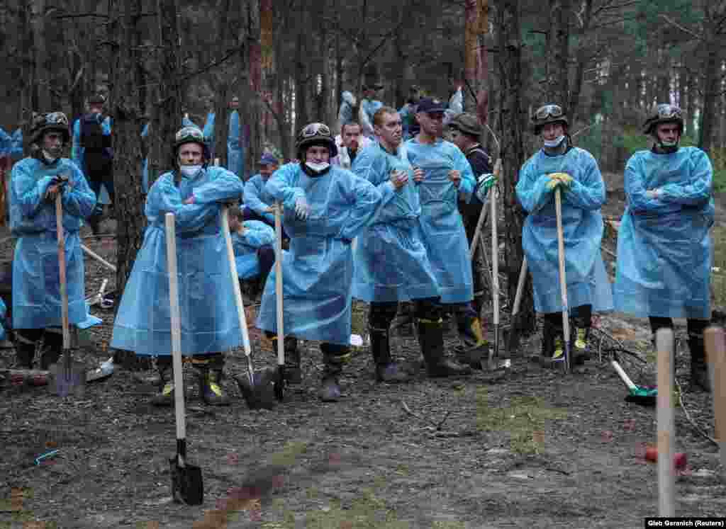 Members of Ukraine’s Emergency Service rest during work to uncover a mass burial site in Izyum on September 16. After Izyum’s recapture, several burial sites, including one containing the bodies of 440 people, were uncovered. 