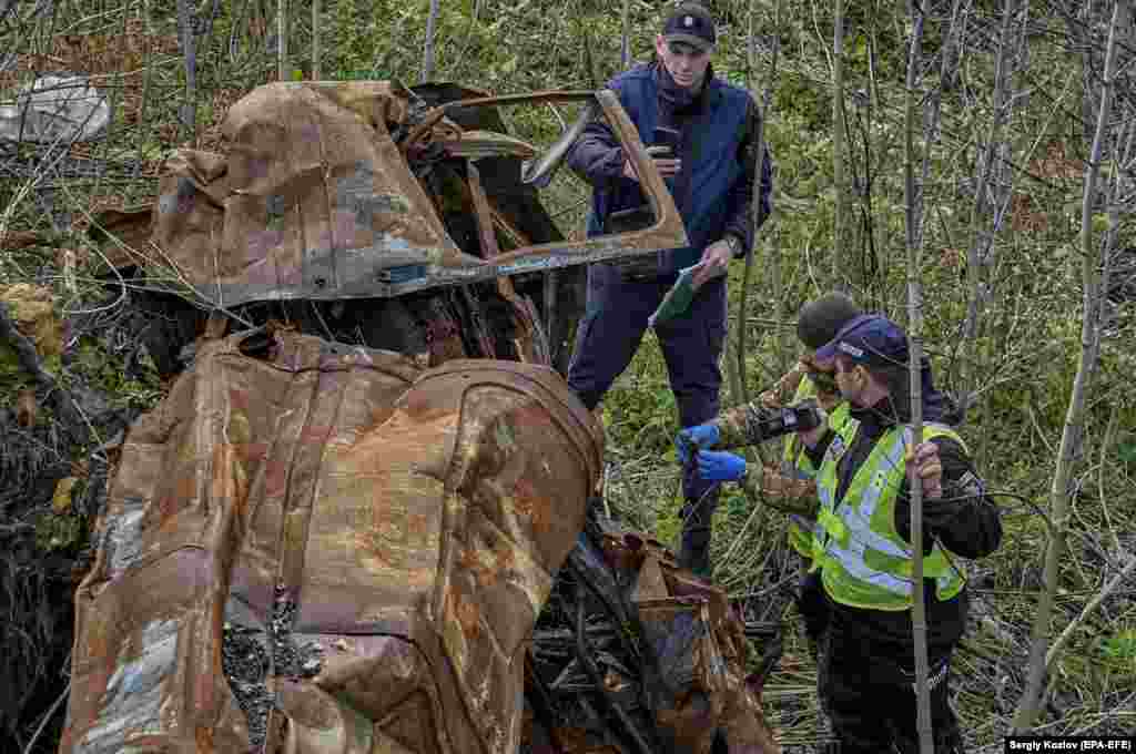 Ukrainian prosecutors and forensics experts examine a burned-out car in Izyum on October 31. According to local witnesses, three people were shot dead by Russian troops in or near this car during the occupation. 