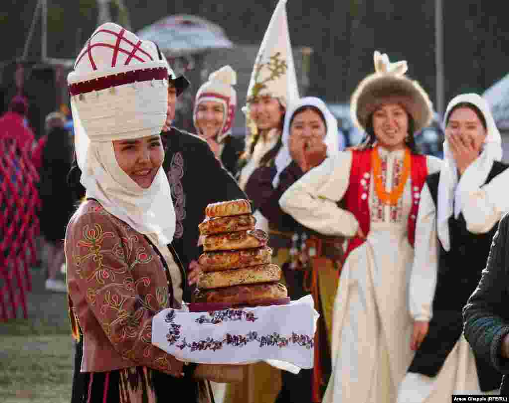 Улуттук кийимчен аялдар конокторду нан менен тосуп турушат. 