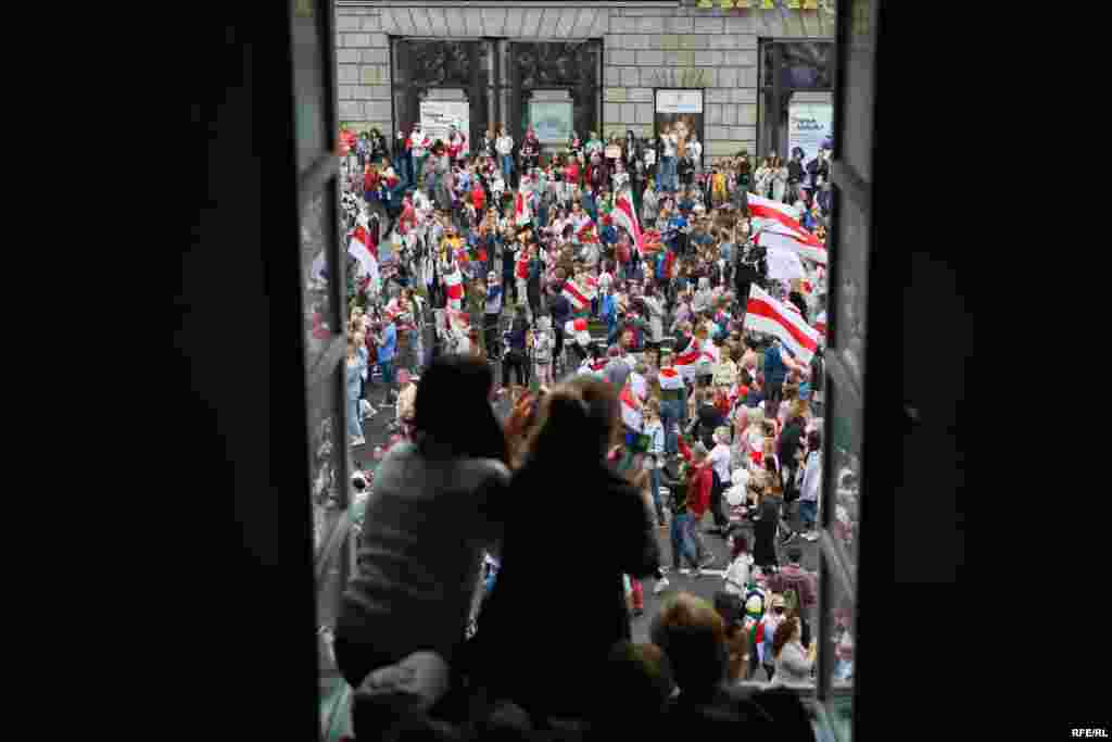 People take pictures of the protesters as they pass by their window in central Minsk. 