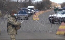 Український військовий зупиняє машини на блокпості в Майорську Донецької області, 16 березня 2020 року
