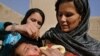 An Afghan woman holds a child as a health worker administers the polio vaccine. The WHO says that large-scale immunization can stop an outbreak.