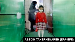 An Iranian elementary schoolgirl passes through a disinfection tunnel as she attends school in north Tehran.