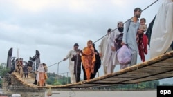 Flood victims cross a temporary bridge as they flee flooded areas of Chakdara, a region in Khyber Pakhtunkhwa Province in early August.