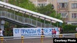 Люди, бегущие вдоль баннера с надписью: «От правды не убежишь». Алматы, 21 апреля 2019 года.