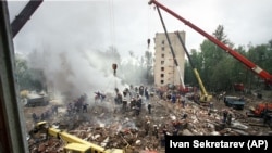 Smoke rises from a destroyed apartment building as Russian Emergency Situations Ministry officers and firefighters try to save people in Moscow on September 13,1999.