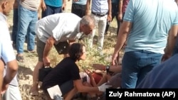 Locals help a wounded cyclist at the scene of the deadly July 29 attack.