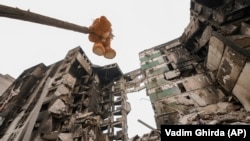Плюшевий ведмедик висить на гілці пошкодженого дерева біля житлового будинку, зруйнованого під час масштабного вторгнення Росії до України. Селище Бородянка Київської області, 5 квітня 2022 року