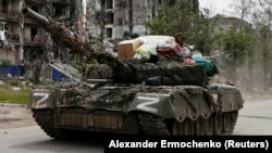 Російські військові на танку в місті Попасна на Луганщині з побутовими речами, які, за словами вимушеної переселенки Аліни Коренюк, були викрадені з її будинку, 26 травня 2022 року