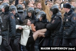 Russian riot police detain a young female demonstrator during an opposition rally in central Moscow on March 26