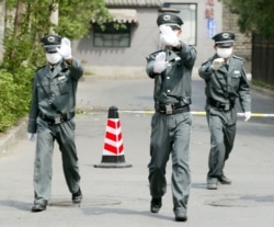 Security guards rush to stop a photo being taken outside a Beijing hospital in April 2003.