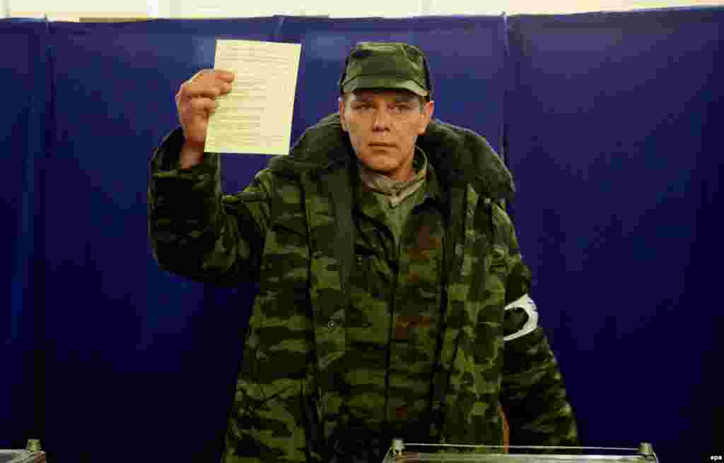 A member of the pro-Russian "self-defense" forces that emerged in Crimea alongside the Russian occupation shows his ballot at a polling station.