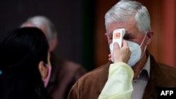 A Bosnian medical worker checks patients' temperatures as they arrive at a vaccination station in Sarajevo.