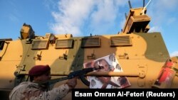 A member of Libyan National Army (LNA) commanded by Khalifa Haftar, points his gun at the image of Turkish President Recep Tayyip Erdogan on a Turkish military armored vehicle, which LNA said they confiscated during Tripoli clashes.