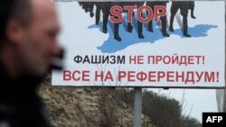A man walks passed a billboard reading "STOP, fascists won't pass, let's all go to the referendum" on the main road entering the Crimean city of Sevastopol.