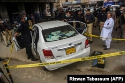 Investigators examine the scene where gunmen opened fire on two Chinese workers in Karachi in July 2021.
