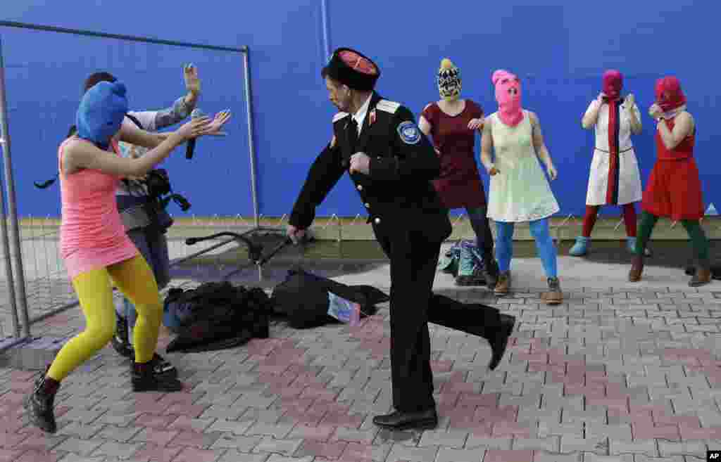 A Cossack attacks Nadezhda Tolokonnikova and a photographer as she and fellow members of the punk group Pussy Riot stage a protest performance in Sochi.