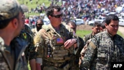 A U.S. officer speaks with a fighters from the Kurdish YPG at the site of Turkish air strikes near the northeastern Syrian Kurdish town of Derik in April.