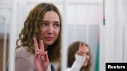 Katsyaryna Andreyeva and Daryya Chultsova, Belarusian journalists working for the Polish television channel Belsat, accused of coordinating mass protests in 2020 by broadcasting live reports, flash the victory sign at a court hearing in February 2021.