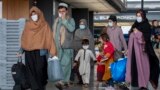 Kabuldan ewakuasiýa edilen owganystanly maşgalalar Waşingtonyň Dulles aeroportyndan ýöräp barýarlar. Sentýabr, 2021 ý.